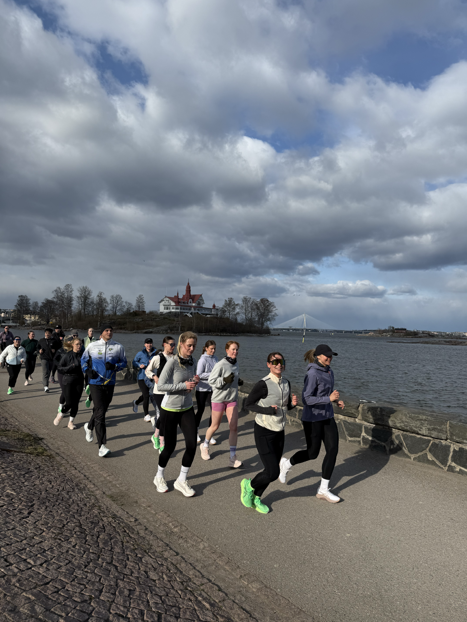 Juoksijat rannassa