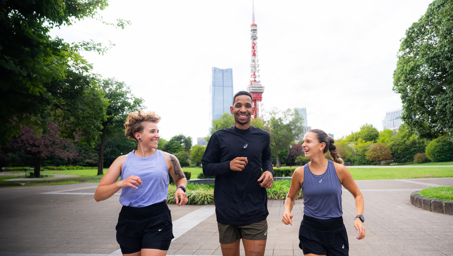 A man and a woman jogging in a park with a skyline in the background