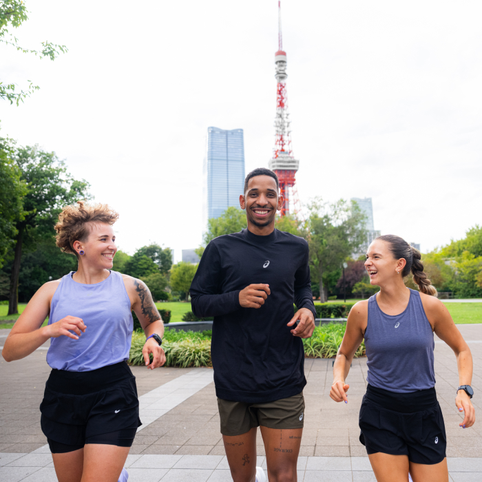 A man and a woman jogging in a park with a skyline in the background